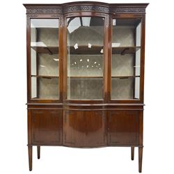 Edwardian mahogany display cabinet, break-bow-front with moulded cornice over blind fretwork frieze, enclosed by two glazed doors, fitted with two cupboards, on square tapering supports