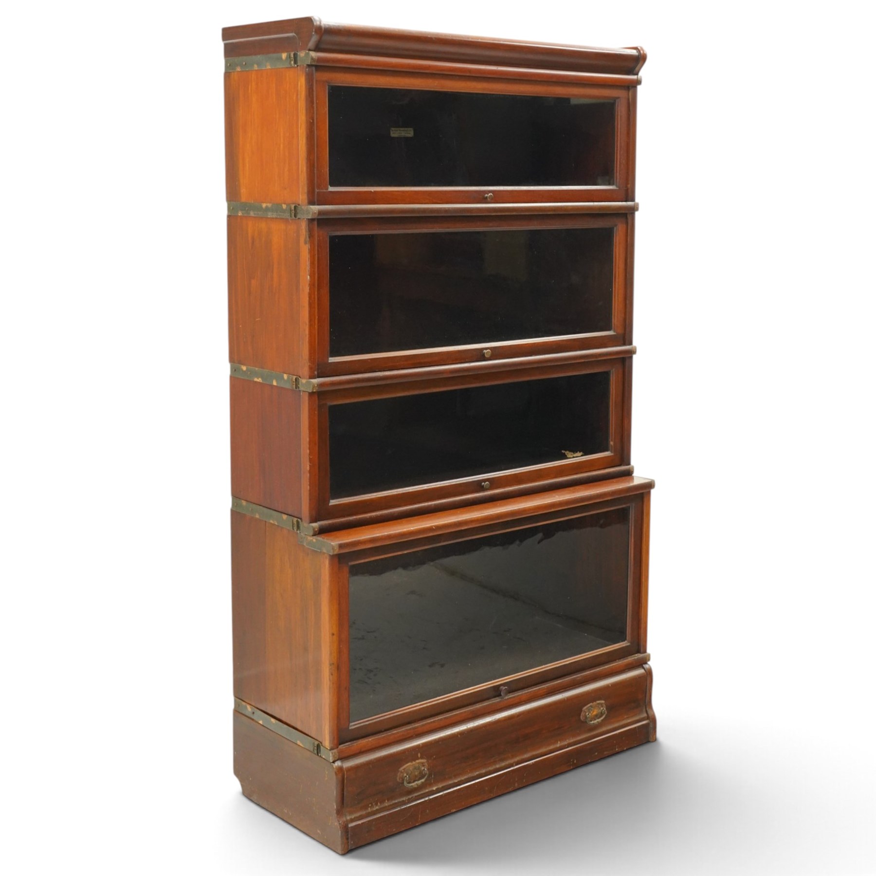 Globe Wernicke - early 20th century mahogany four-tier stacking library bookcase, the shelves fitted with glazed up-and-over doors, fitted with single drawer to the skirted base