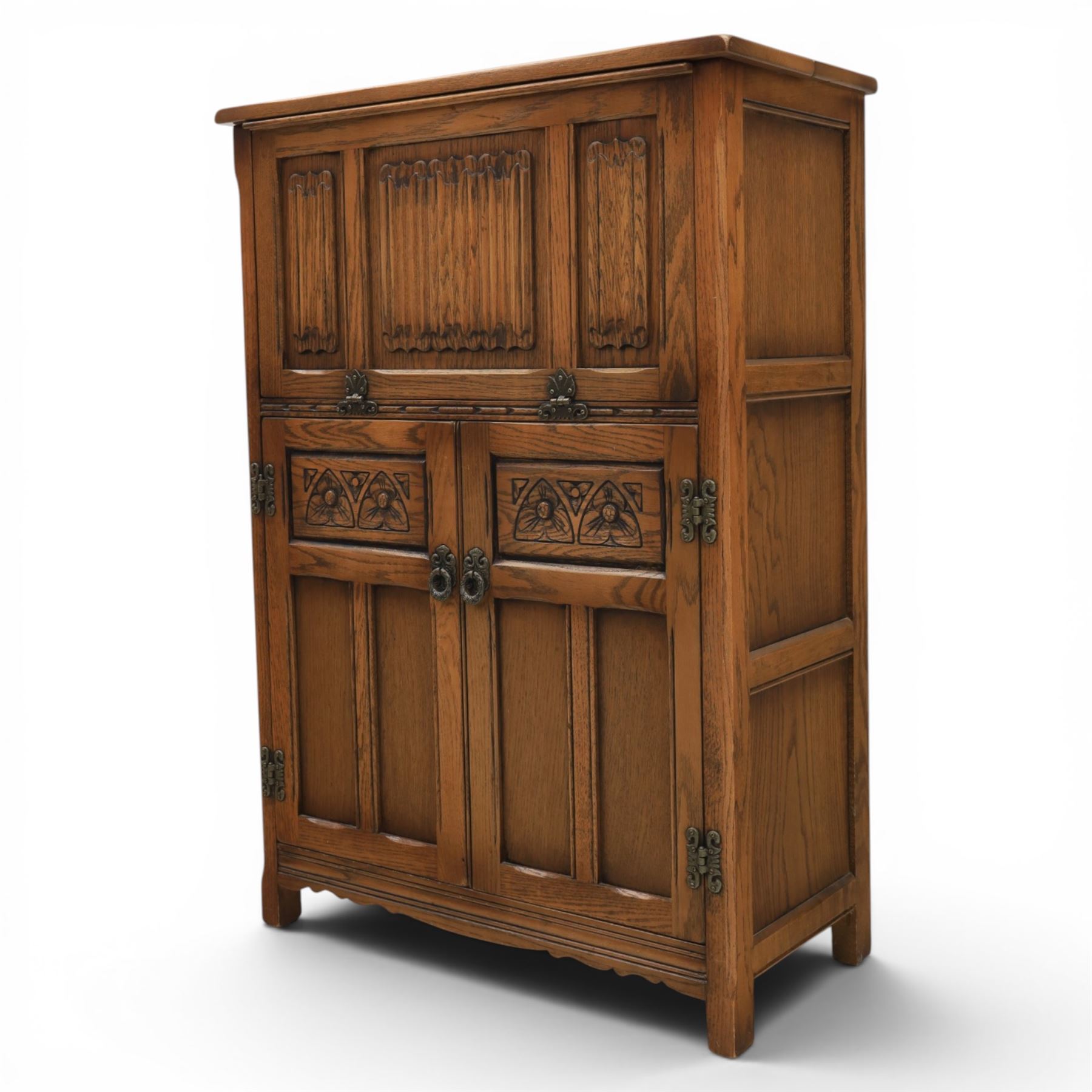 Old Charm - carved oak bar with three bar stools and associated Old Charm drinks cabinet, carved top with channels for glassware beneath, bar surface above glazed panels, shelves for glassware to the back, associated Old Charm drinks cabinet with fall front linenfold carving, above twin doors with shelved interior