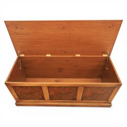 Traditional design figured elm blanket chest, with padded striped upholstered seat, over a hinged top with panelled sections below raised on a plinth base