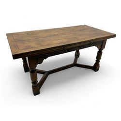 Early 20th century Jacobean design draw-leaf oak dining table, rectangular top with carved frieze depicting scrolling foliage and grape clusters, sliding extending leaves, raised on robust turned supports united by H-stretcher  