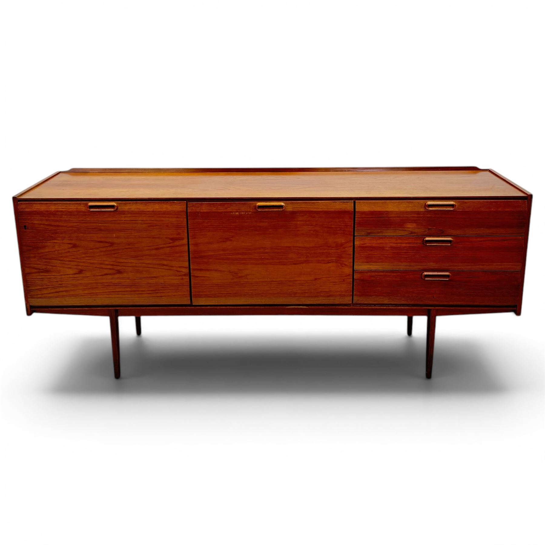 BCM (Bath Cabinet Makers) - mid-20th century teak sideboard, rectangular top with back gallery, left hand side fall front cupboard, centre cupboard opening to reveal a shelved interior, the right side with a bank of three drawers one fitted for cutlery, raised on inset tapering supports