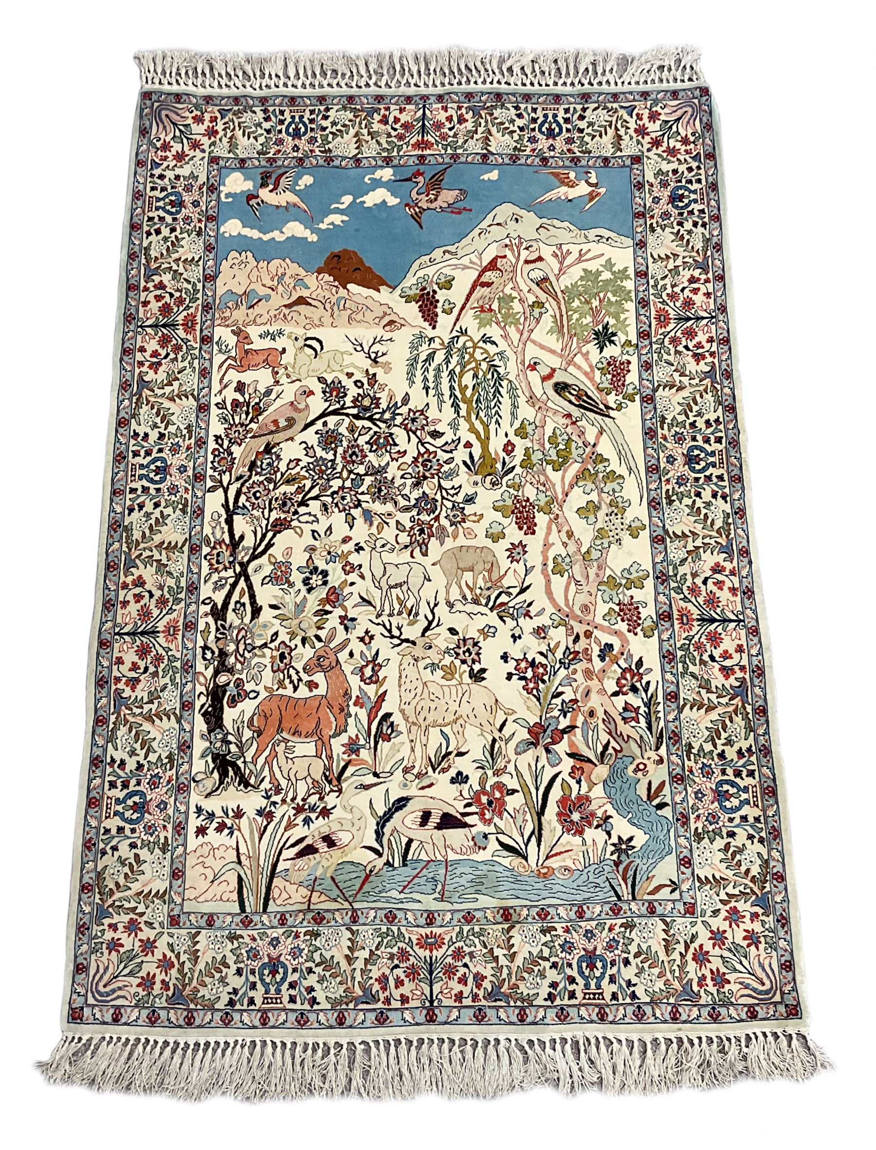 Fine Persian tree of life rug wall hanging, ivory ground field depicting landscape filled with animals, birds and flowers, the guarded border with stylised flower heads and foliage decoration, with brass hanging rail