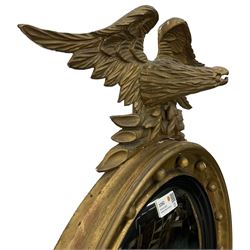 Early 20th century Regency design gilt convex wall mirror, with eagle pediment surmounted over moulded frame applied with spherical mounts, ebonised and moulded inner slip