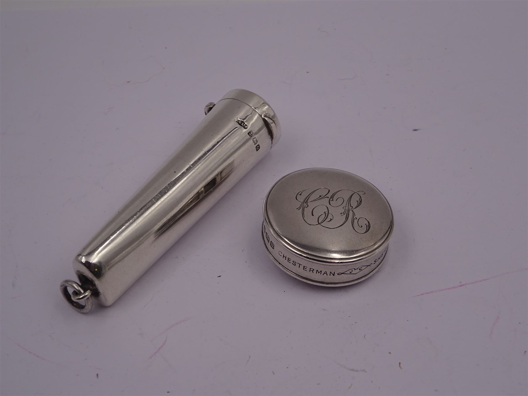 Early 20th century silver tape measure, of circular form, engraved with monogram, inscribed Chesterman Sheffield England to edge, hallmarked James Chesterman & Co, Sheffield 1912 together with a 1930s silver cheroot holder case, hallmarked Joseph Gloster Ltd, Birmingham 1938 containing a cheroot holder with hallmarked 9ct gold collar 