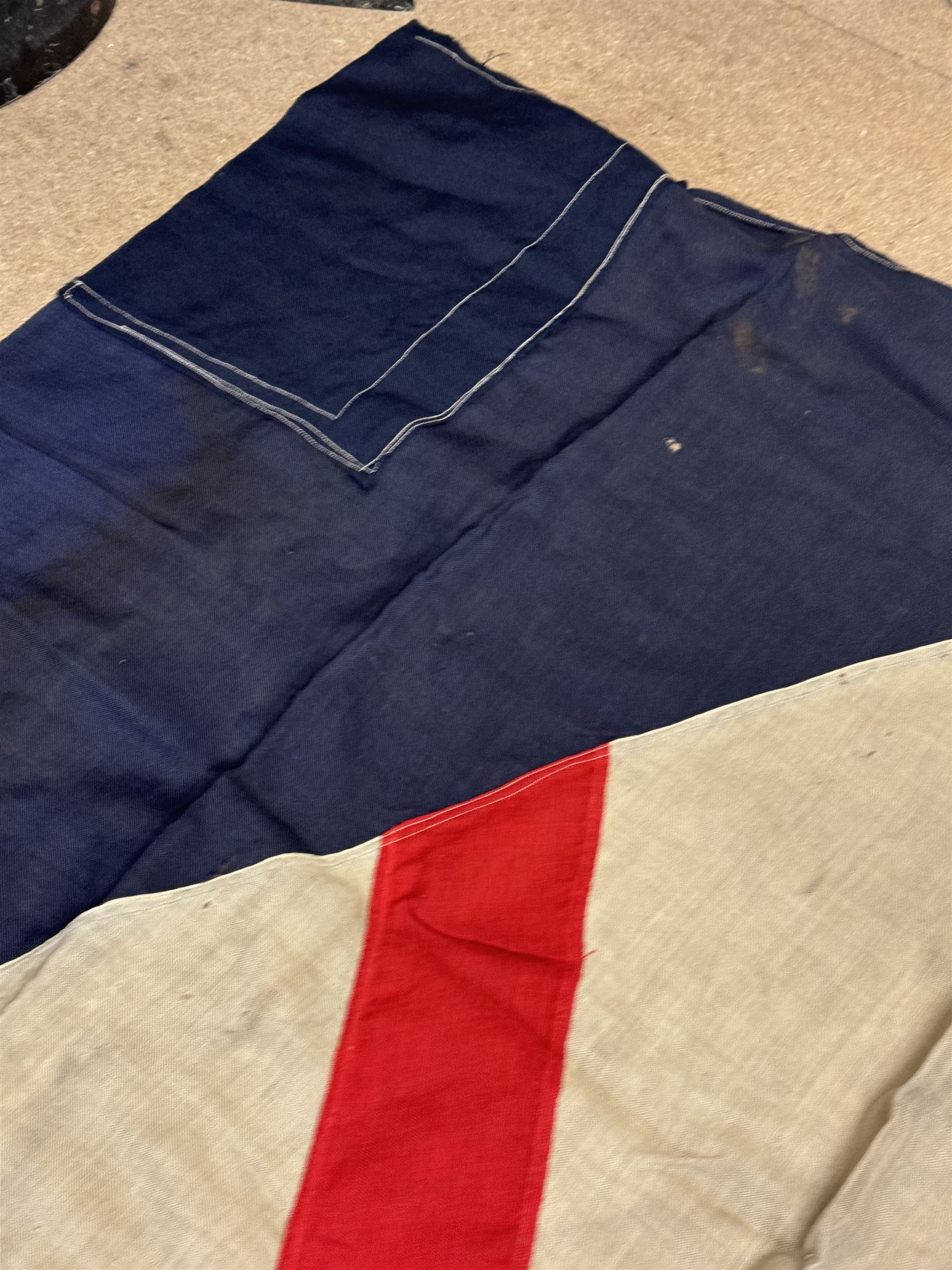 Ship's house flag, rectangular linen flag, with a white diamond and red cross to the centre, upon a cobalt blue ground, inscribed on the hoist 'Cutty Sark', H130cm, W170cm

Provenance by vendor repute: Vendor's father was a naval cadet in 1940s/50s on board HMS Worcester which was moored alongside the Cutty Sark on the River Thames at Greenhithe. He has had the flag since then. 