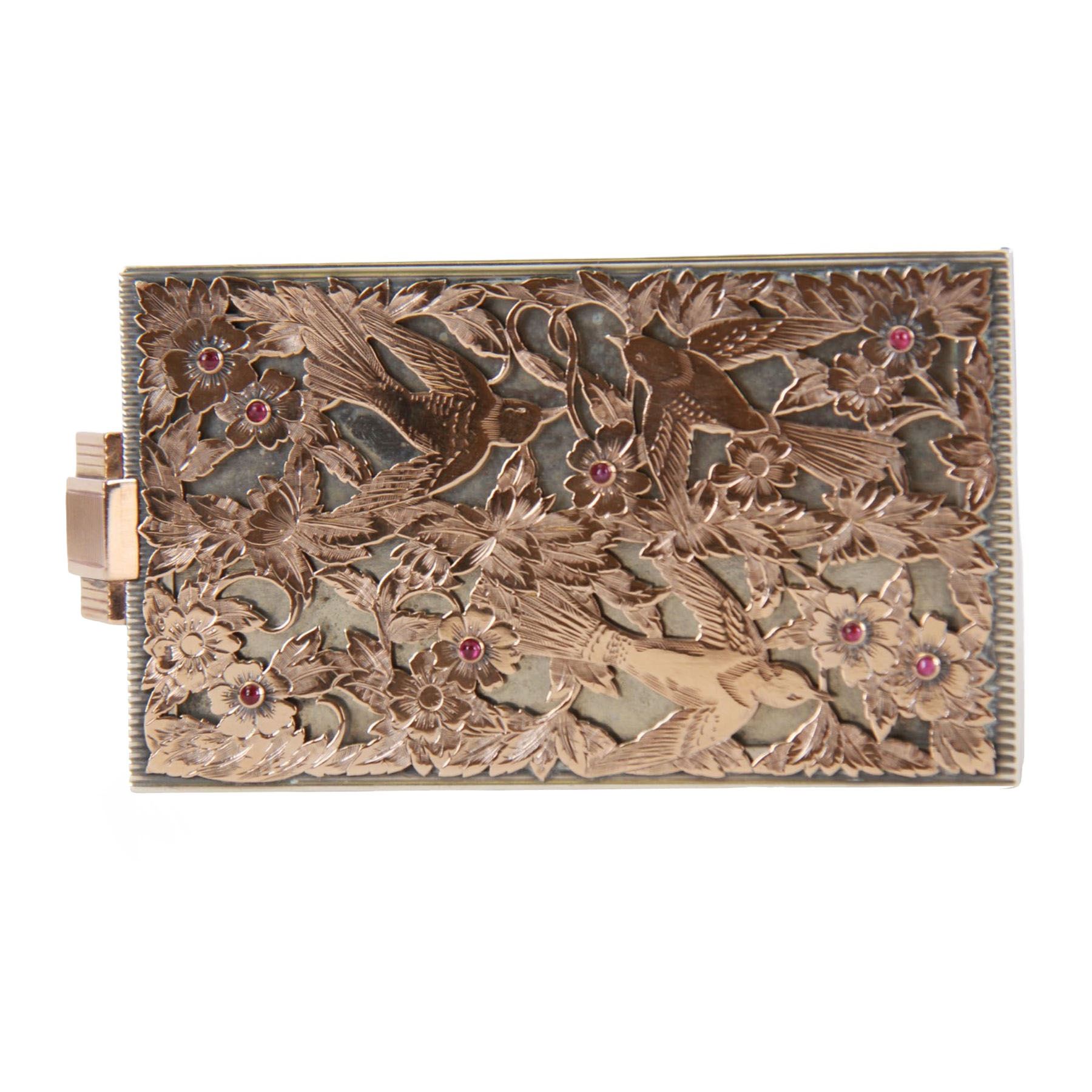 Mid 20th century French silver and gold vanity case, of rectangular form, the hinged cover decorated with an openwork panel of bids and cabochon ruby studded flower heads, opening via a pull clasp to reveal a mirror to the underside and compartment with lift up cover, signed J. Lacloche Paris Cannes, and bearing French assay marks, not including clasp L10cm W6cm D1.5cm

