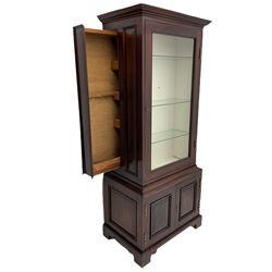 Mahogany display cabinet with hidden compartment, projecting cornice over single glazed door enclosing glass shelves, double panelled cupboard below, the interior with button releasing sliding back compartment, on bracket feet