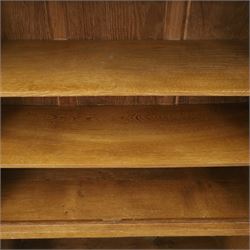Rabbitman - oak glazed bookcase or display cabinet, lightly adzed rectangular top with raised gallery, twin glazed doors enclosing two shelves, over a pair of panelled cabinet doors with wrought iron fittings, with carved rabbit signature, by Peter Heap of Wetwang