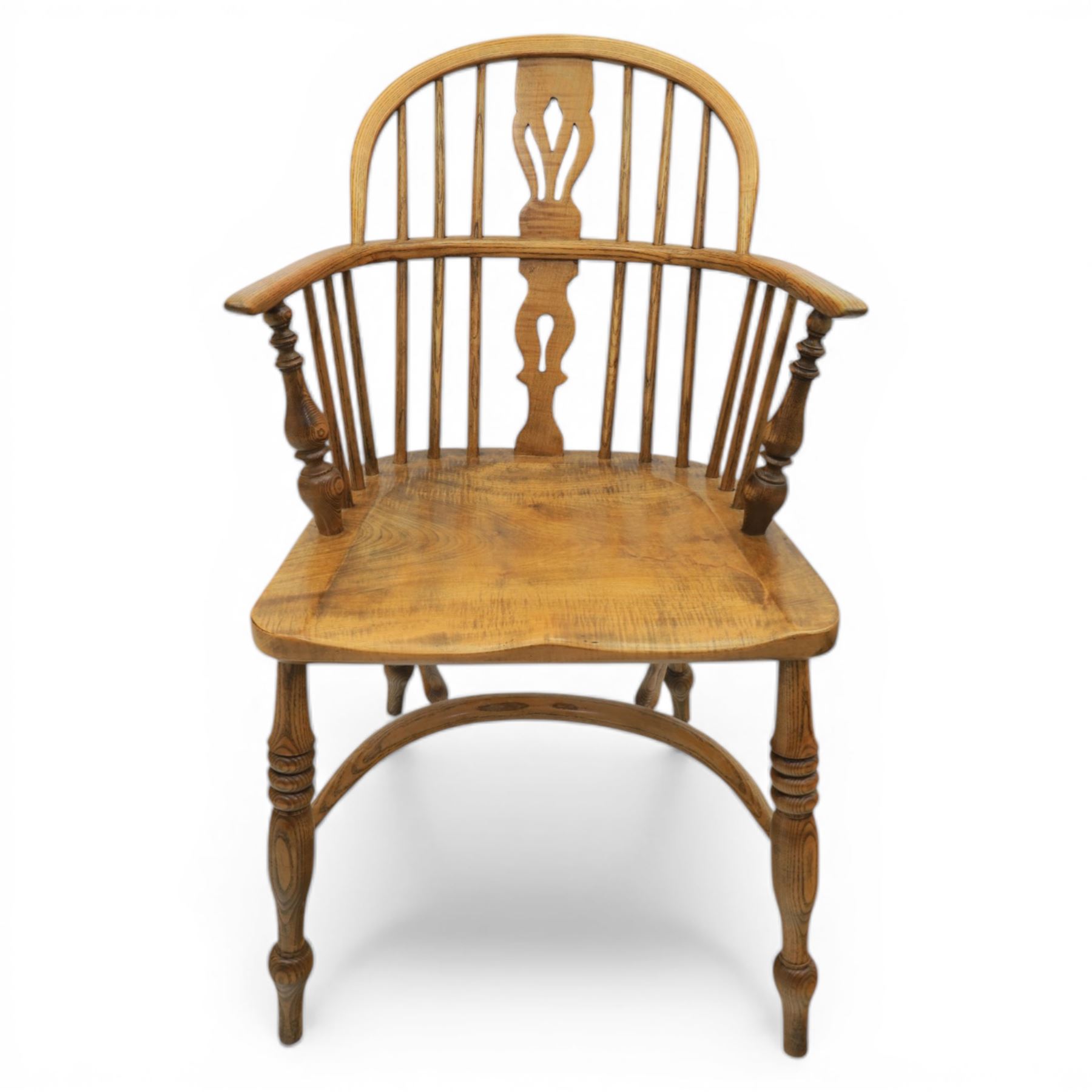 Late 20th century elm and beech low back country Windsor armchair, the arched hoop back with central pierced splat and turned spindles, shaped arm rail on turned supports, saddle seat, raised on turned legs united by a crinoline stretcher