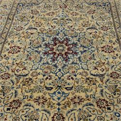 Central Persian fine Nain hand-knotted rug, ivory ground, with a central shaped floral medallion with pendants, surrounded by scrolling foliate and floral motifs incorporating rosettes, palmettes and delicate vine work in blue, cream and beige tones, enclosed by blue spandrels and an ivory border with repeating palmettes and meandering vines, flanked by floral guard stripes, with cotton fringes