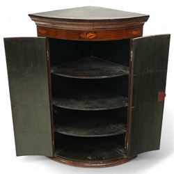 George III inlaid mahogany cylinder corner cupboard, projecting moulded cornice over figured frieze inlaid with shell motifs, two doors with checkered stringing enclosing three shelves, circa 1800