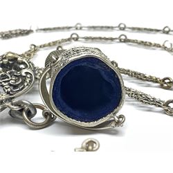 19th century continental silver plated chatelaine, the main body flanked with winged mythical beasts and central soldier slaying a dragon supporting three suspended items to include velvet lined small basket and long clasped filigree chain, together with a thimble