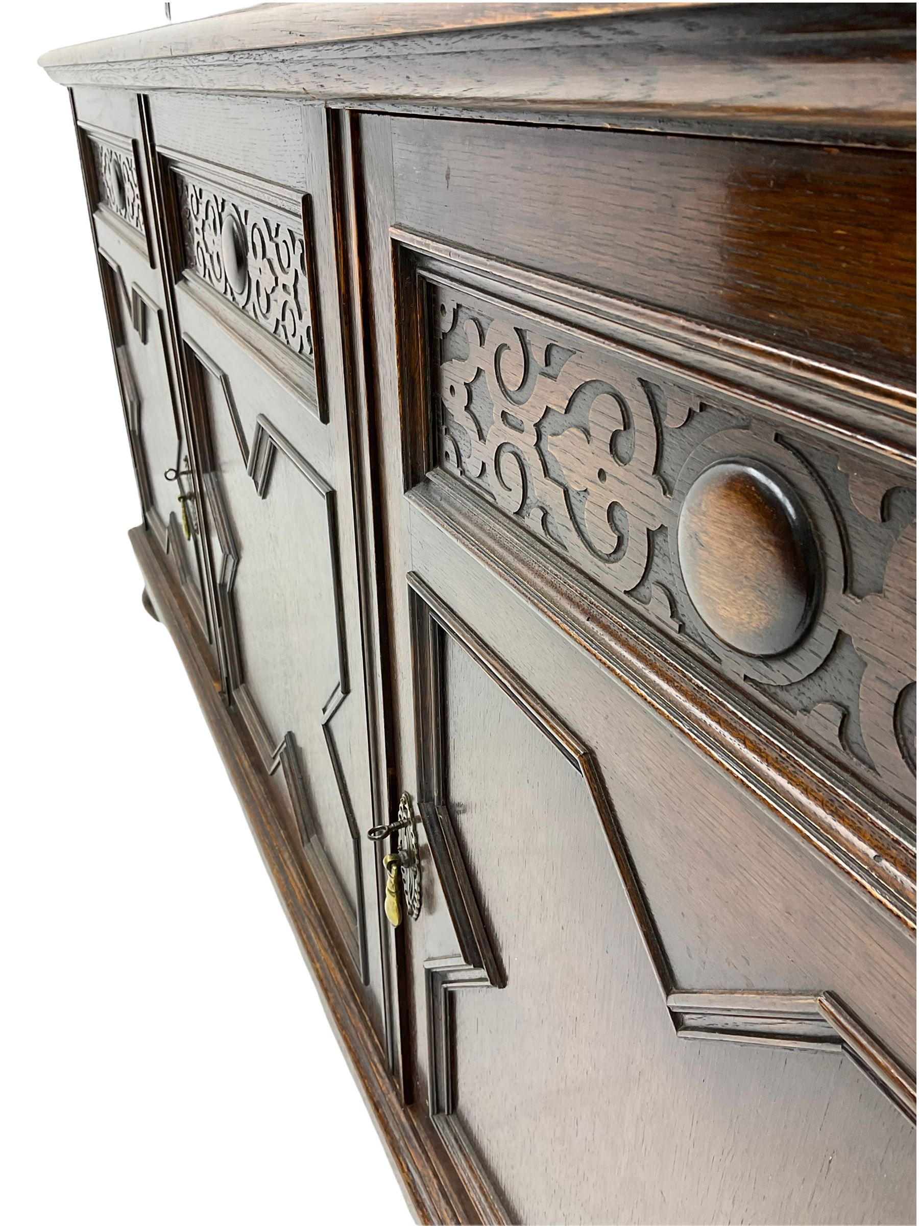 Waring and Gillow - oak bookcase on cupboard, projecting cornice over arcade frieze, guilloche upright decoration, the top section enclosed by three astragal glazed doors, the lower section enclosed by three geometric panelled doors with blind fretwork decoration, on turned feet