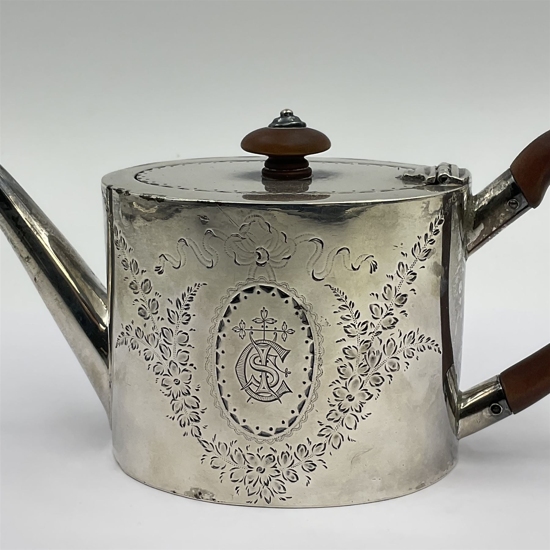 George III silver bachelors teapot, of oval form with wooden scroll handle and finial, the body chased with armorial crest and ribbon swag and foliate detail, hallmarked Samuel Godbehere & Edward Wigan, London 1793, including handle H9cm