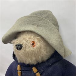 Pair of Paddington Bear teddies with amber eyes, the first example having a brown felt hat, red coat and blue PB boots with original label; the second having a grey felt hat, blue coat and blue Dunlop boots, tallest H51cm 