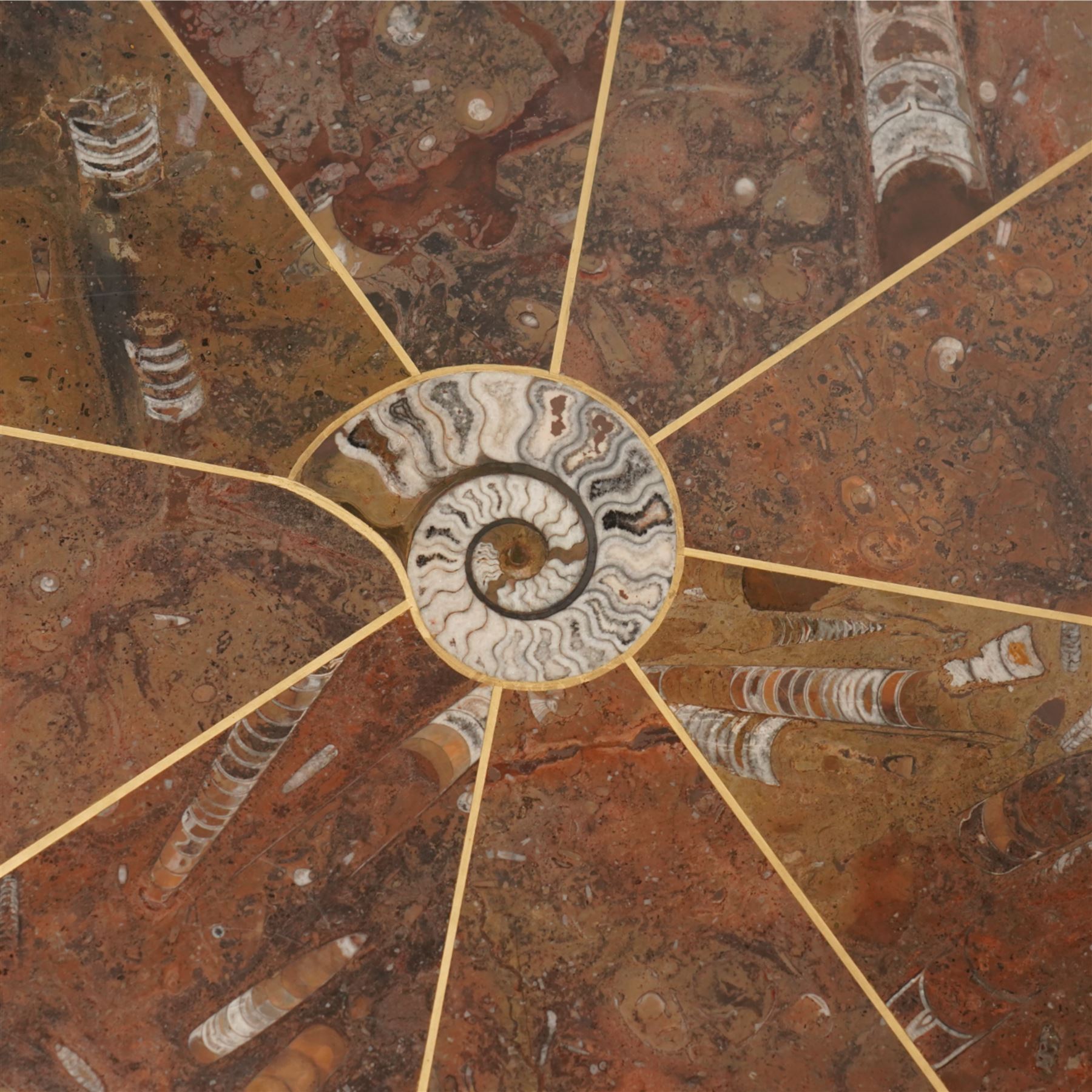 Octagonal specimen table with brass inlay, the limestone tabletop with a central ammonite and orthoceras and goniatite inclusions, upon a stepped octagonal base 
