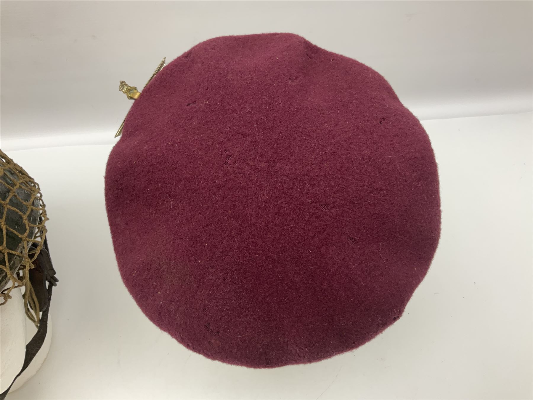 WW2 British Airborne Troops/Paratroopers Steel Helmet with green textured paint finish and netting cover, leather and sponge liner and three point chinstrap mounting; liner marked BMB 1943; together with a paratrooper's maroon beret with metal badge (2)