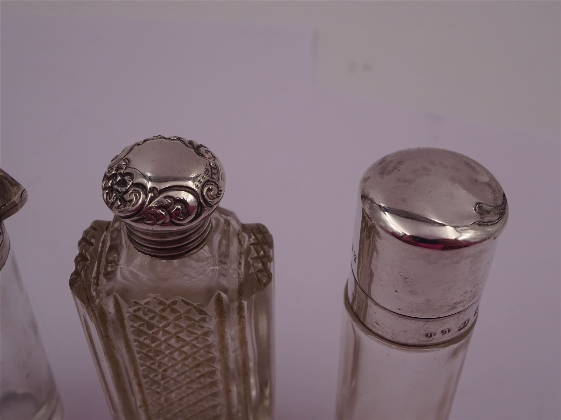 Four silver mounted glass scent bottles, including a Victorian cut glass example with embossed silver cover, and three cylindrical plain glass examples, on with engine turned decoration, three with glass stoppers, together with a pair of silver salts and spoons, all hallmarked, tallest H8cm