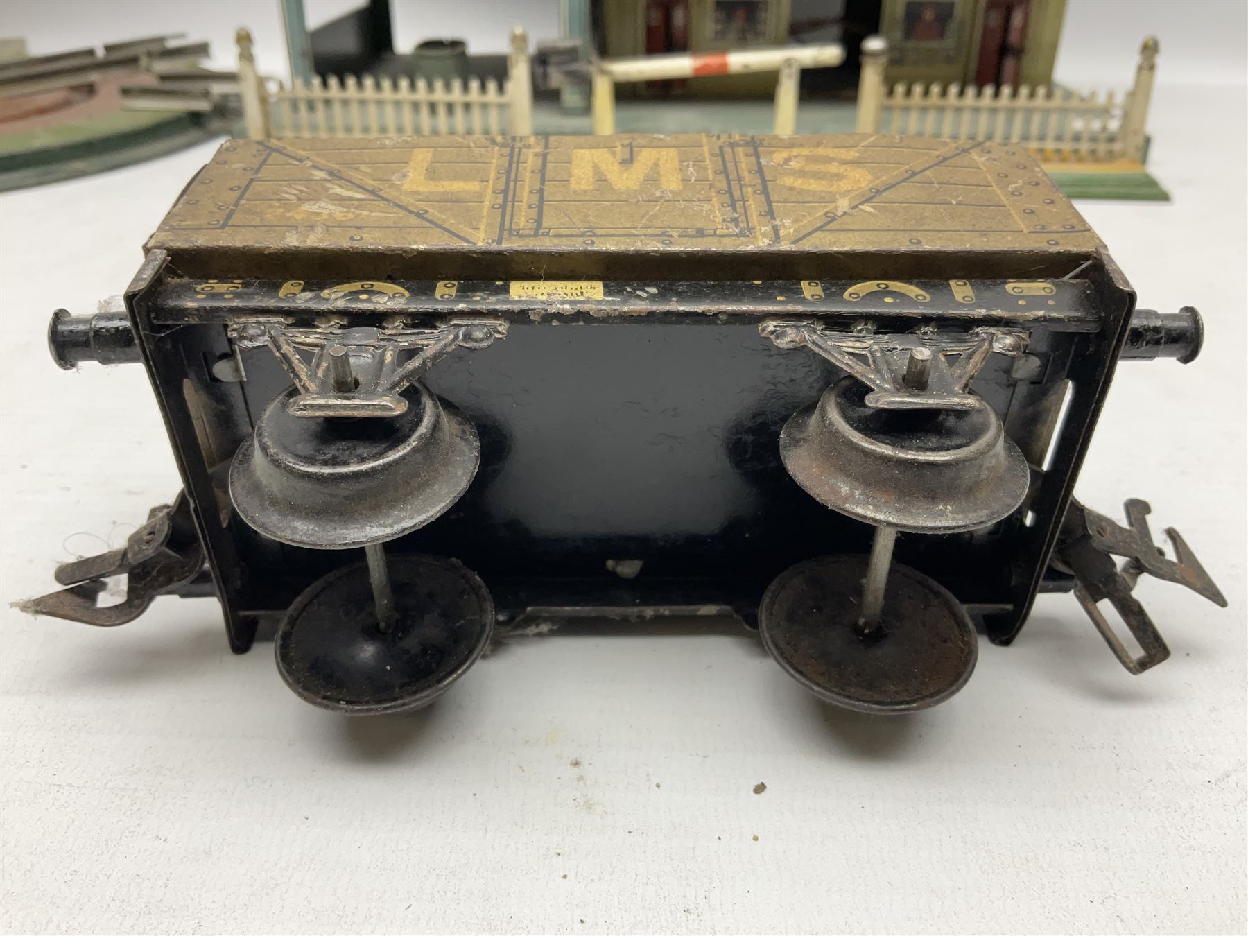 '0' gauge - Bing tin-plate two-storey double sided station with open walk-through to one end, rail side canopy, hinged doors and removable roof giving access to clock illumination L35cm; Bing hand-cranked turntable and open wagon; Marklin tin-plate level crossing barrier and Newspaper vendor's tin-plate four-wheel hand cart (5)