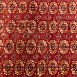 Vintage Bokhara hand-knotted rug, madder field woven in rows of octagonal Tekke guls arranged in vertical columns, each enclosing angular cruciform devices and tribal motifs, divided by narrow indigo lines, within multiple geometric borders incorporating stepped lozenges and latch hook devices, with cotton fringe ends 