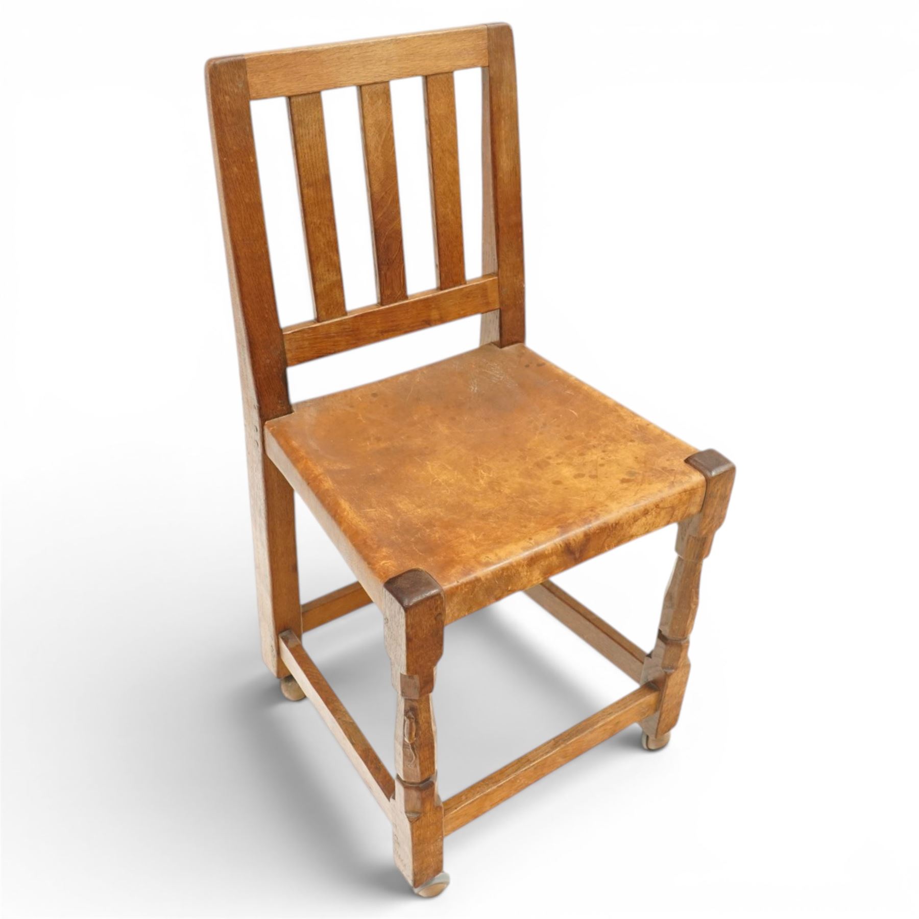 Mouseman - 1940s oak side chair, the slat-back over a slung leather seat, raised on octagonal front supports united by box stretcher, carved with slim mouse signature, by the workshop of Robert Thompson of Kilburn