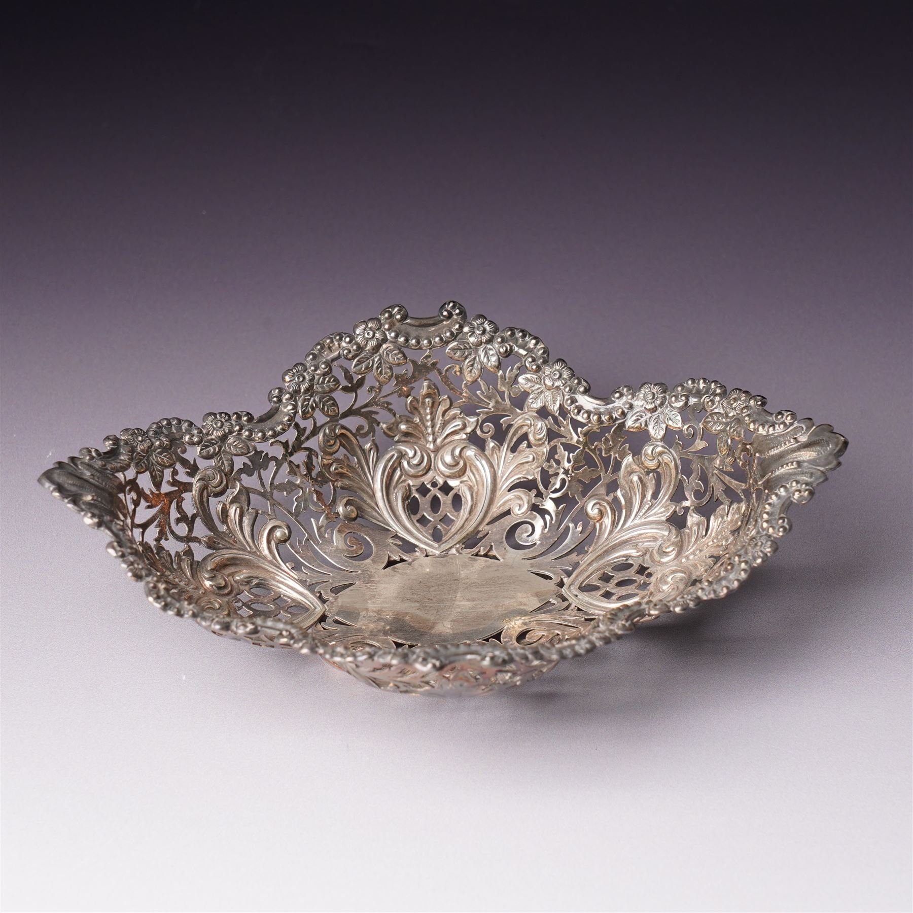 Edwardian silver oval dressing table box, the hinged cover embossed with angel heads W10cm London 1902 Maker William Comyns & Sons and an Edwardisn pierced silver oval sweetmeat basket L18cm Sheffield 1907 Maker James Dixon & Sons Ltd