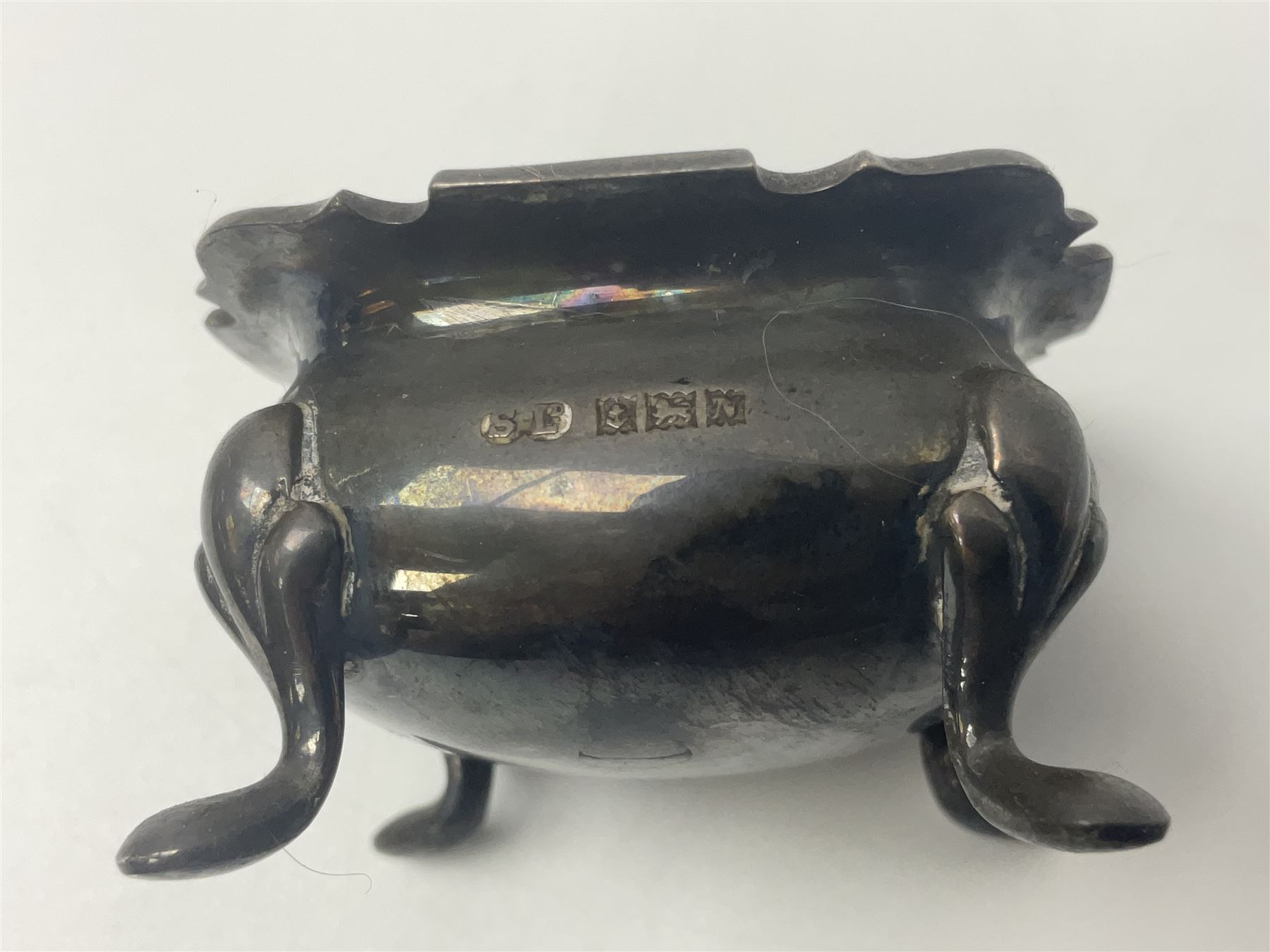 Modern two piece silver cruet set, comprising pepper shaker and open salt, each with shaped rims and upon four pad feet, hallmarked William Suckling Ltd, Birmingham 1962, together with an early 20th century silver open salt, of oval form, hallmarked William Aitken, Birmingham 1918