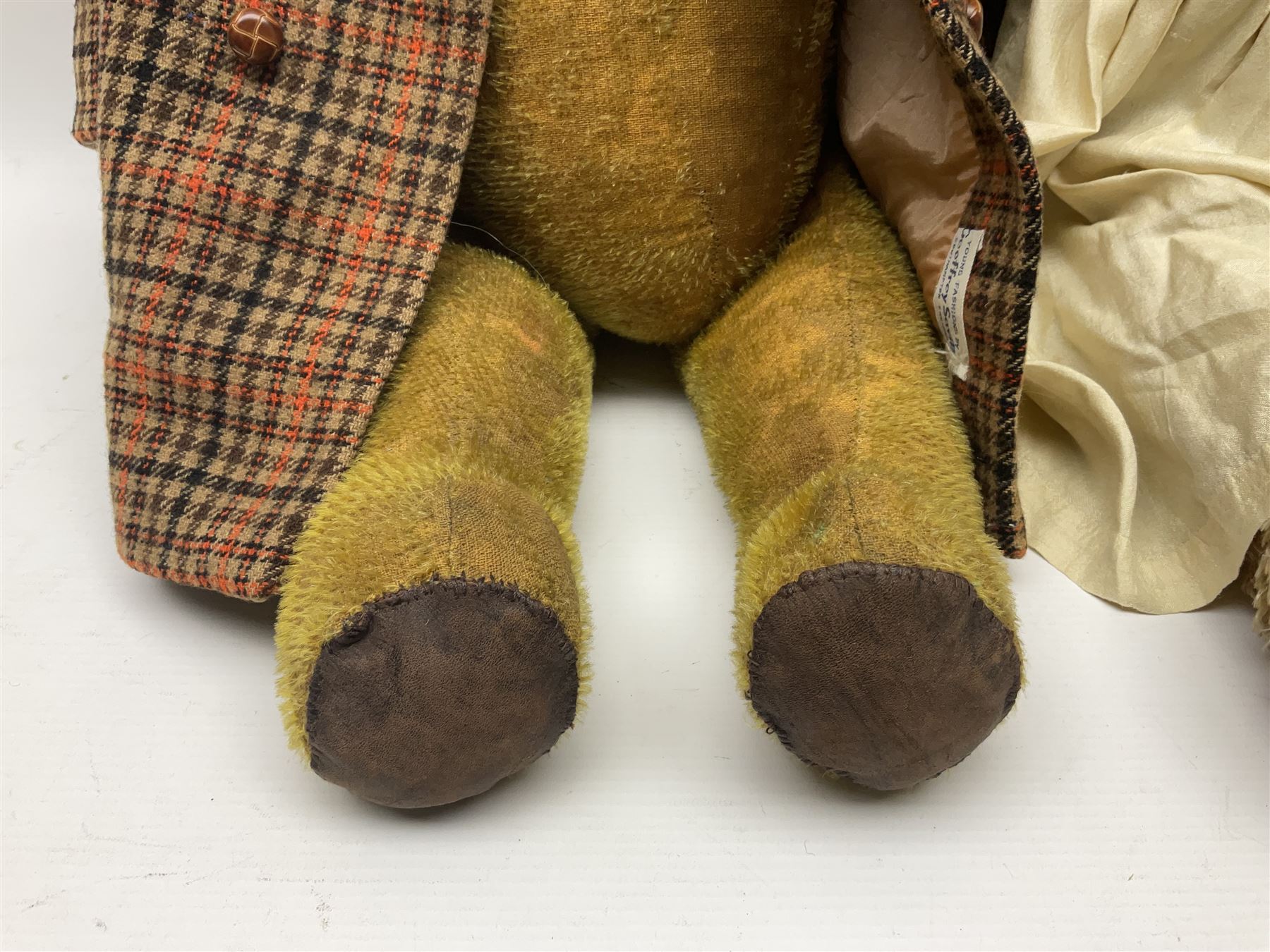 Two early 20th century straw filled jointed teddy bears, first example wearing a tweed jacket bearing Geoffrey Saville label, with leather padded paws and ears, horizontally stitched nose and humpback; second example with applied eyes, vertically stitched nose and faux leather paw pads, both with growler mechanisms, tallest H74cm 