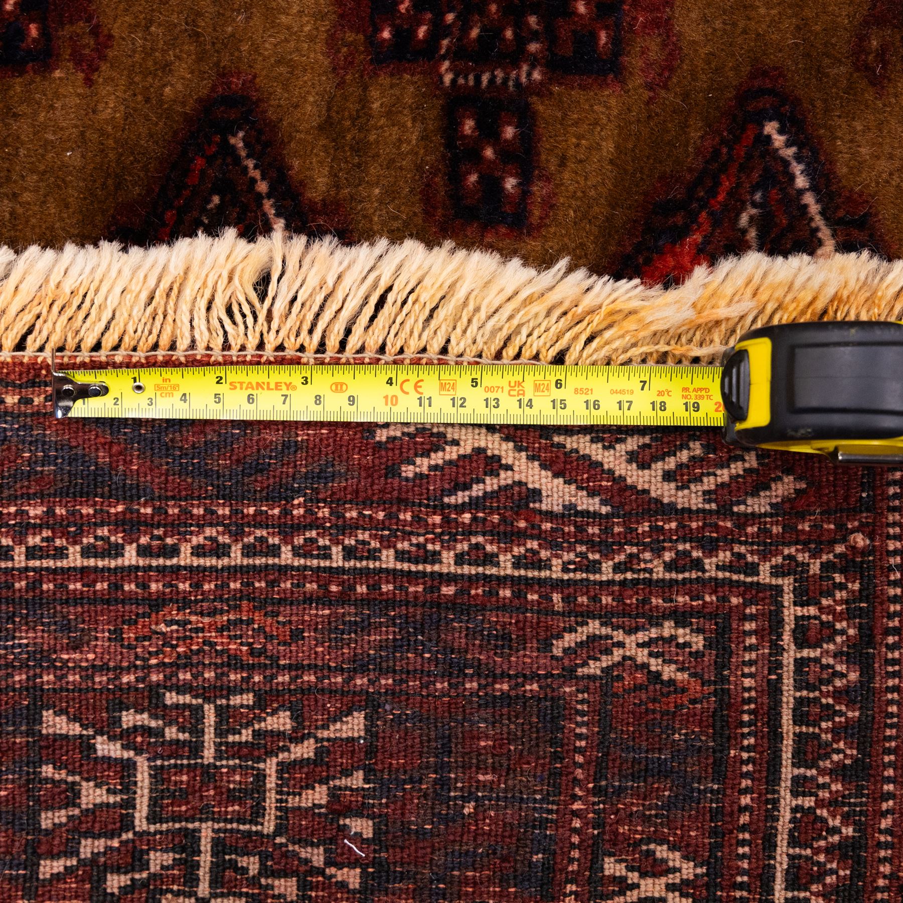 North East Persian Turkoman hand-knotted rug, camel brown field decorated with repeating rows of octagonal guls, interspersed with small geometric motifs enclosed within narrow guard borders in a palette of madder red, brown, and ivory, with cotton fringe ends  