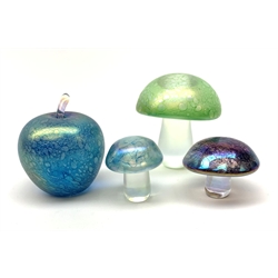 Three John Ditchfield Glasform iridescent mushroom paperweights, two with paper labels beneath, largest H9cm, together with a John Ditchfield Glasform apple paperweight, in iridescent blue, with paper label beneath. 