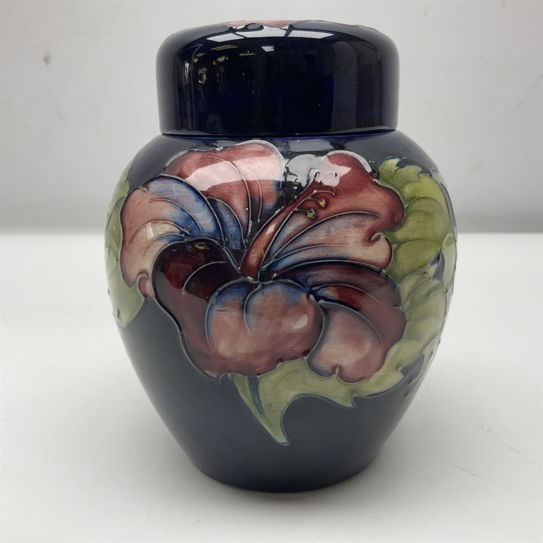 Moorcroft ginger jar, decorated in the Hibiscus pattern upon a cobalt blue ground,  with impressed Moorcroft, Made in England marks beneath and paper label detailed Potters to the late Queen Mary, H15cm