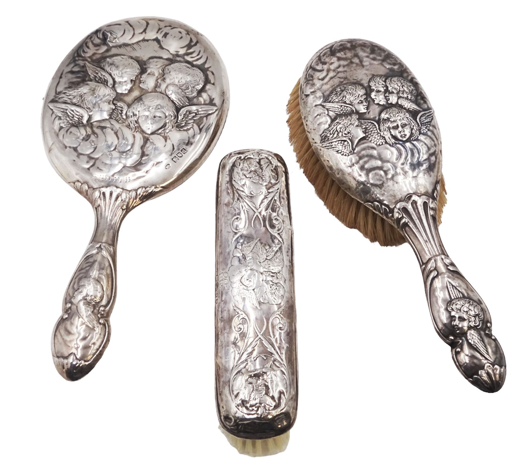 Victorian silver hand mirror, decorated in relief with putti and engraved Edith, hallmarked William Comyns & Sons, London 1899, together with a similar silver hair brush, hallmarked Birmingham 1910, maker's mark indistinct and a clothes brush, hallmarks worn and indistinct