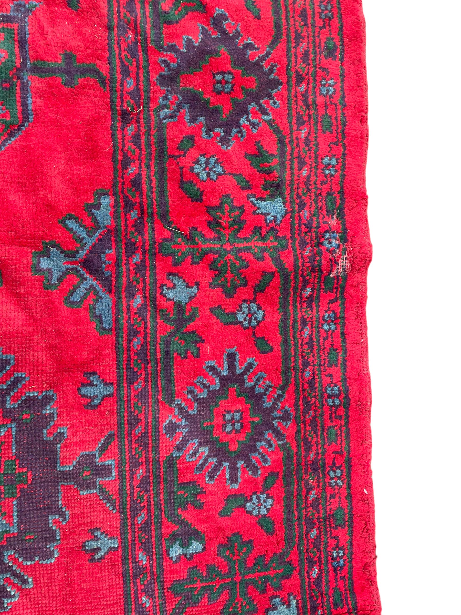 Early 20th century Western Anatolia Turkish Oushak crimson ground carpet, decorated with large Palmettes with trailing branches, the main border decorated with repeating stylised motifs within guard stripes 