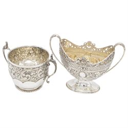 Late Victorian silver twin handled sugar bowl, profusely embossed with floral and scrolling decoration and acanthus capped handles, upon stepped oval base, hallmarked Josiah Williams & Co, London 1897, together with a Victorian twin handled sugar bowl, of circular form with embossed and chased foliate decoration and seated figures capping each handle, upon circular base, hallmarked London 1888, maker's mark indistinct, tallest H11cm