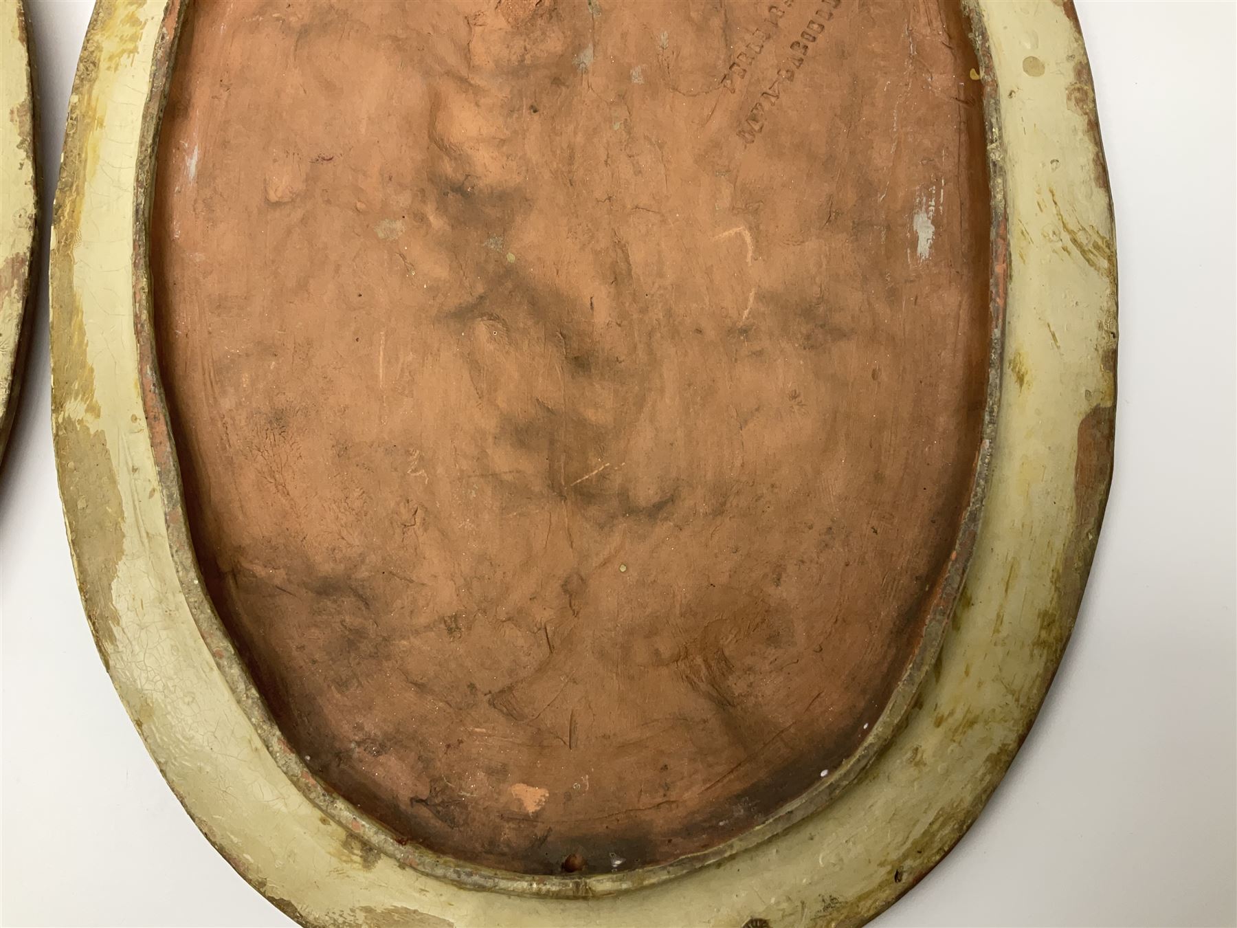 Pair of 19th century classical terracotta relief wall plaques depicting the goddess Hygeia and another goddess, seated holding an ewer, each of oval form, indistinctly signed, each stamped Ferreira verso, H42cm, W30cm