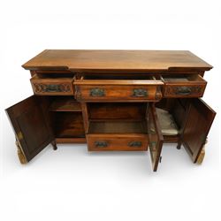 Late 20th century Art Nouveau walnut sideboard, the moulded rectangular top above a run of three drawers, the outer drawers with blind fretwork decoration and applied metal handles, the centre drawer with scroll carved terminals, below a central mirrored cupboard door with oval panel and pierced surround, flanked by carved panel doors with sinuous foliate motifs, on turned supports