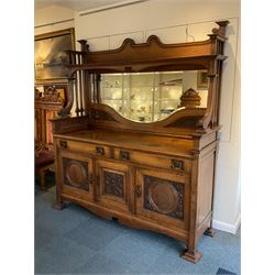 Late 19th century Arts & Crafts period oak mirror back sideboard, shaped bevelled mirror back carved with foliate scrolls and flower heads, down swept supports with elongated club-shaped uprights, moulded rectangular top over two drawers and three cupboards, the drawer fronts with copper handles decorated with sailing ships, panelled doors carved with mythical beasts, flowerheads and foliage, on moulded block feet