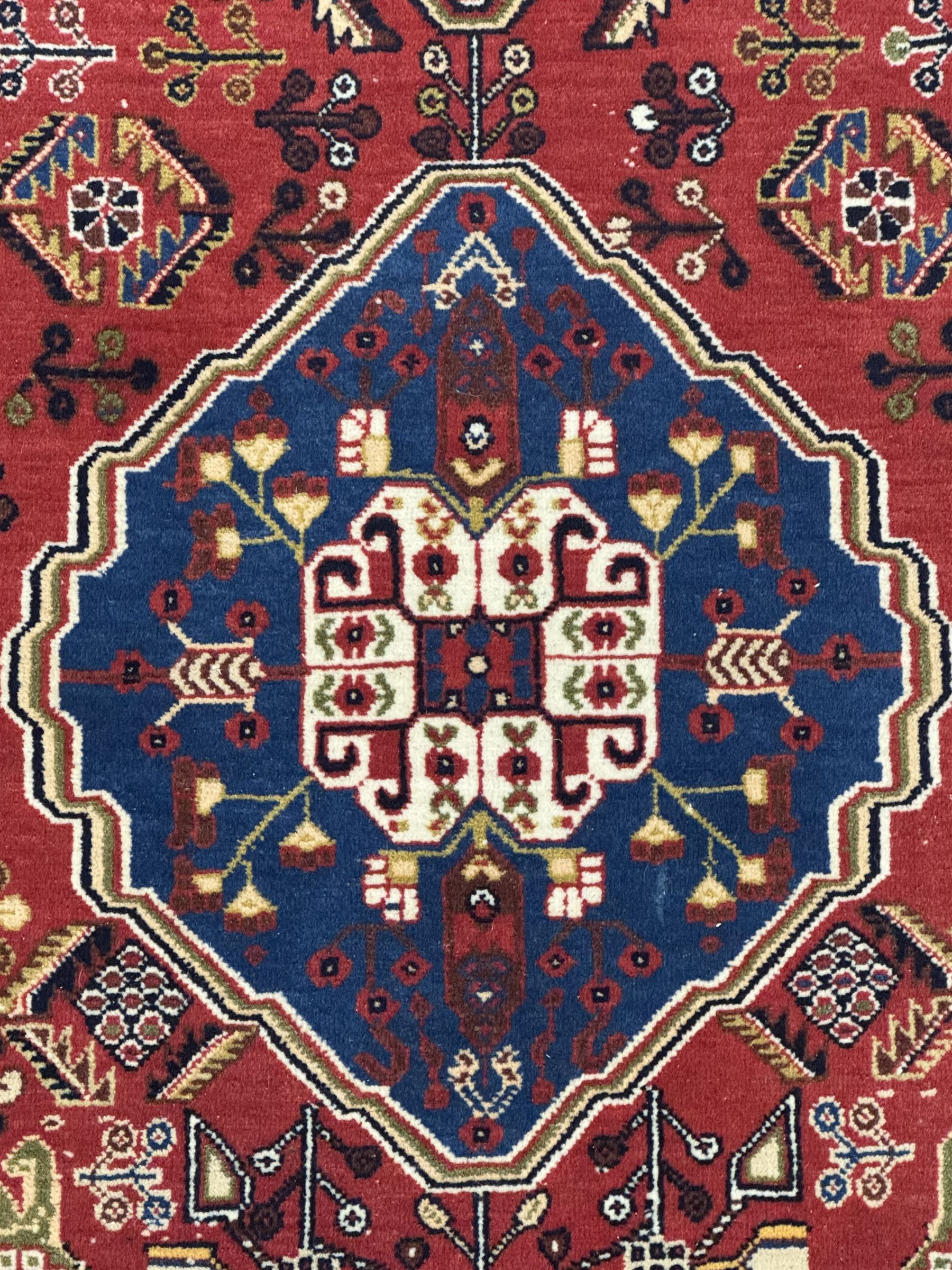 Fine Persian Qashqai crimson and navy ground runner, three large medallions filled with geometric and floral designs, the field with angular vines and stylised floral decoration, wide ivory border decorated with repeating floral and angular motifs