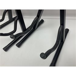 Four folding tubular guitar stands, two by RockJam; and folding tubular saxophone stand (5)