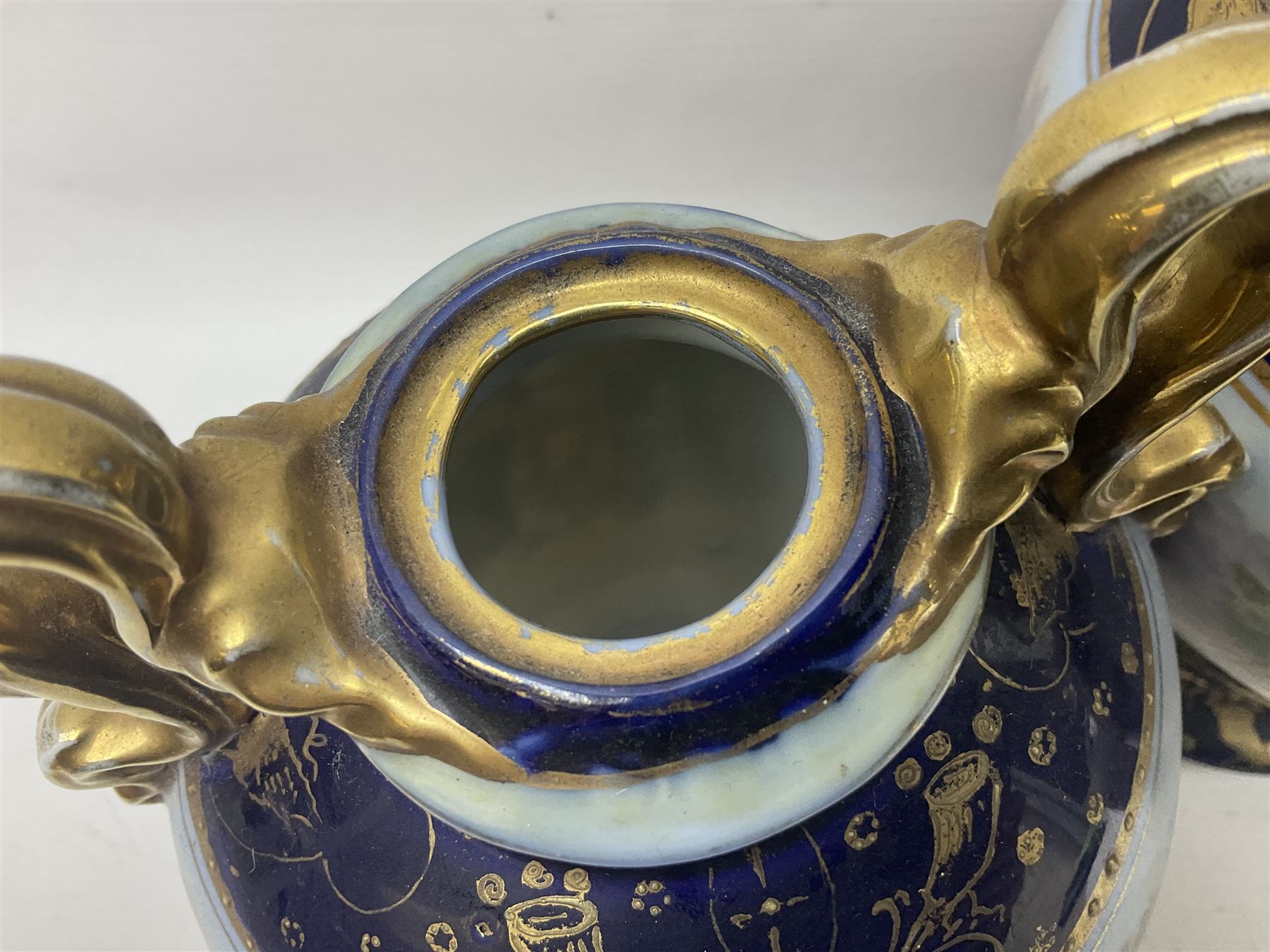 19th century Vienna style porcelain 'Musik' garniture, the central vase of baluster form with domed cover flanked by two smaller vases with twin curved gilt handles to short neck, each decorated with classical figural vignettes between blue borders heightened with gilt, H33.5cm