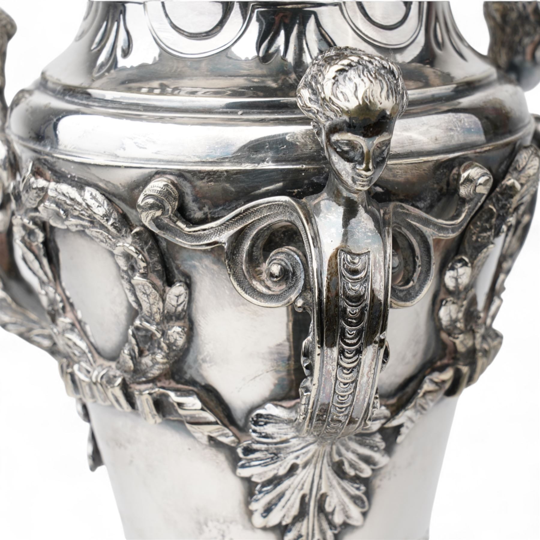 19th century silver plated vase of tapering form with lappet border and three caryatid handles surrounded with laurel wreath cartouches raised on triple paw feet on lobed base H28cm