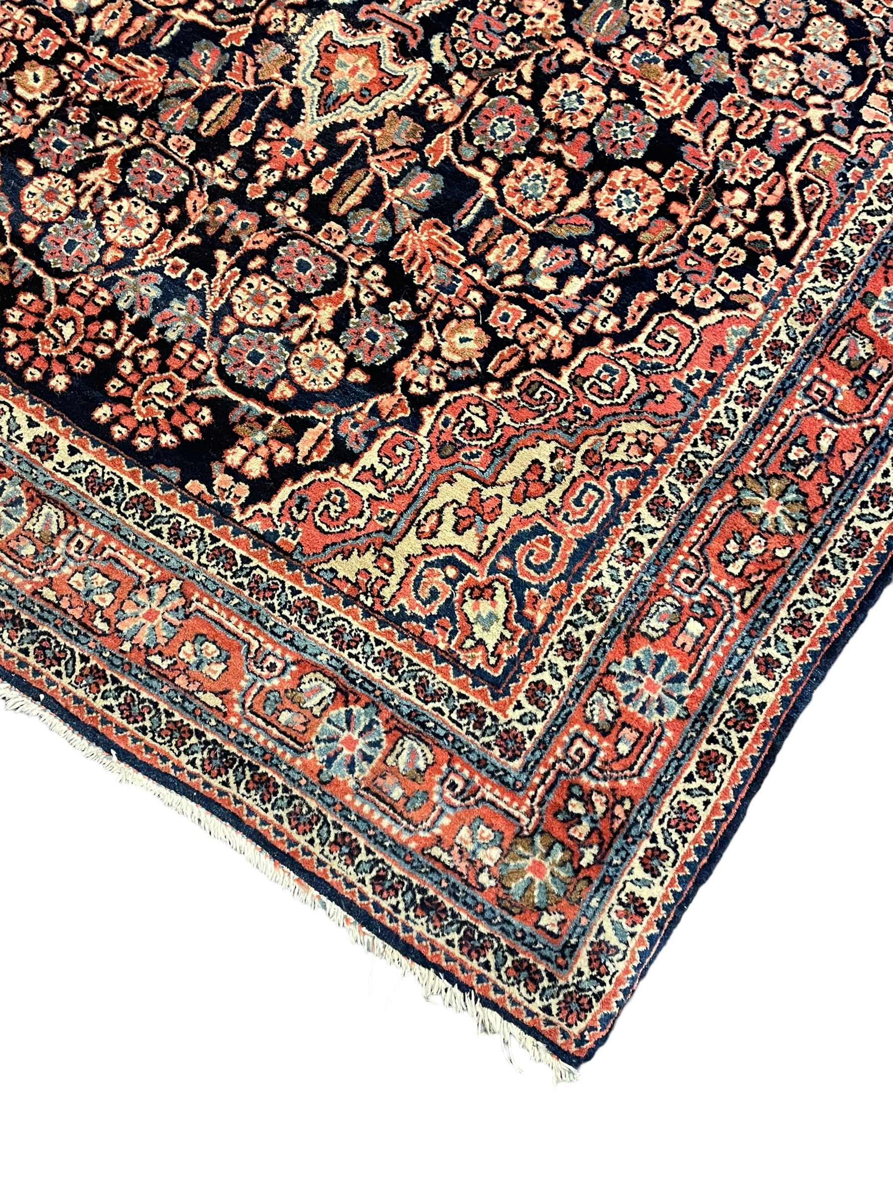 Persian indigo ground rug, the field decorated with intricate interlaced foliage branches and small flower heads, shaped floral design central medallion, the border decorated with scrolling branch and flower heads within guard bands 