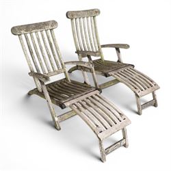 Pair of teak reclining garden steamer armchairs, each with an adjustable slatted back, curved slatted seat and footstool