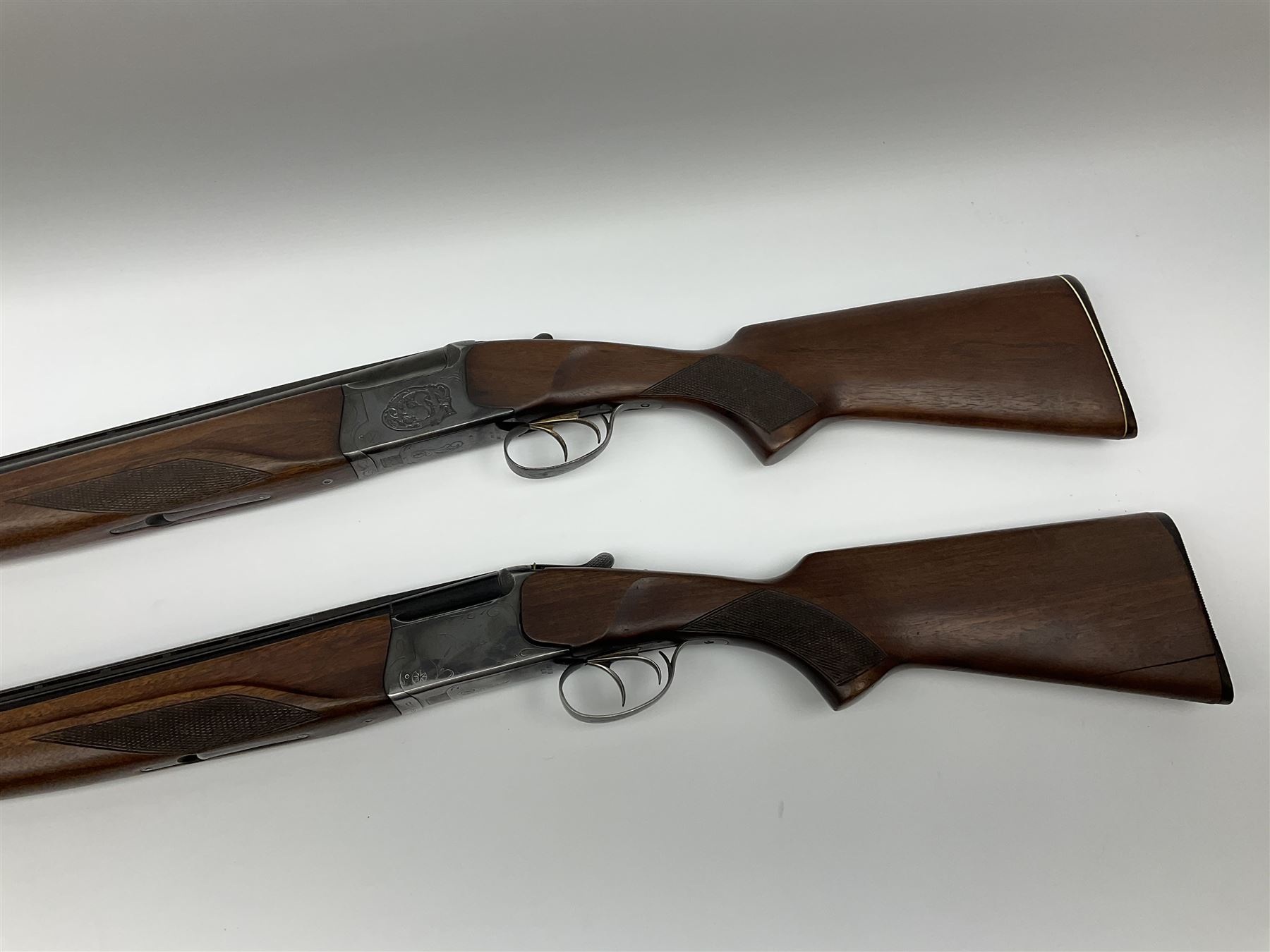 Two Russian Baikal 12-bore over-and-under double barrel boxlock non-ejector sporting guns; one with 68.5cm barrels, walnut stock with chequered pistol grip and fore-end and thumb safety, serial no.520545, L111cm overall; the other with 72.5cm barrels, walnut stock with chequered pistol grip and fore-end and thumb safety, serial no.012448, L114.5cm overall (2) SHOTGUN CERTIFICATE REQUIRED