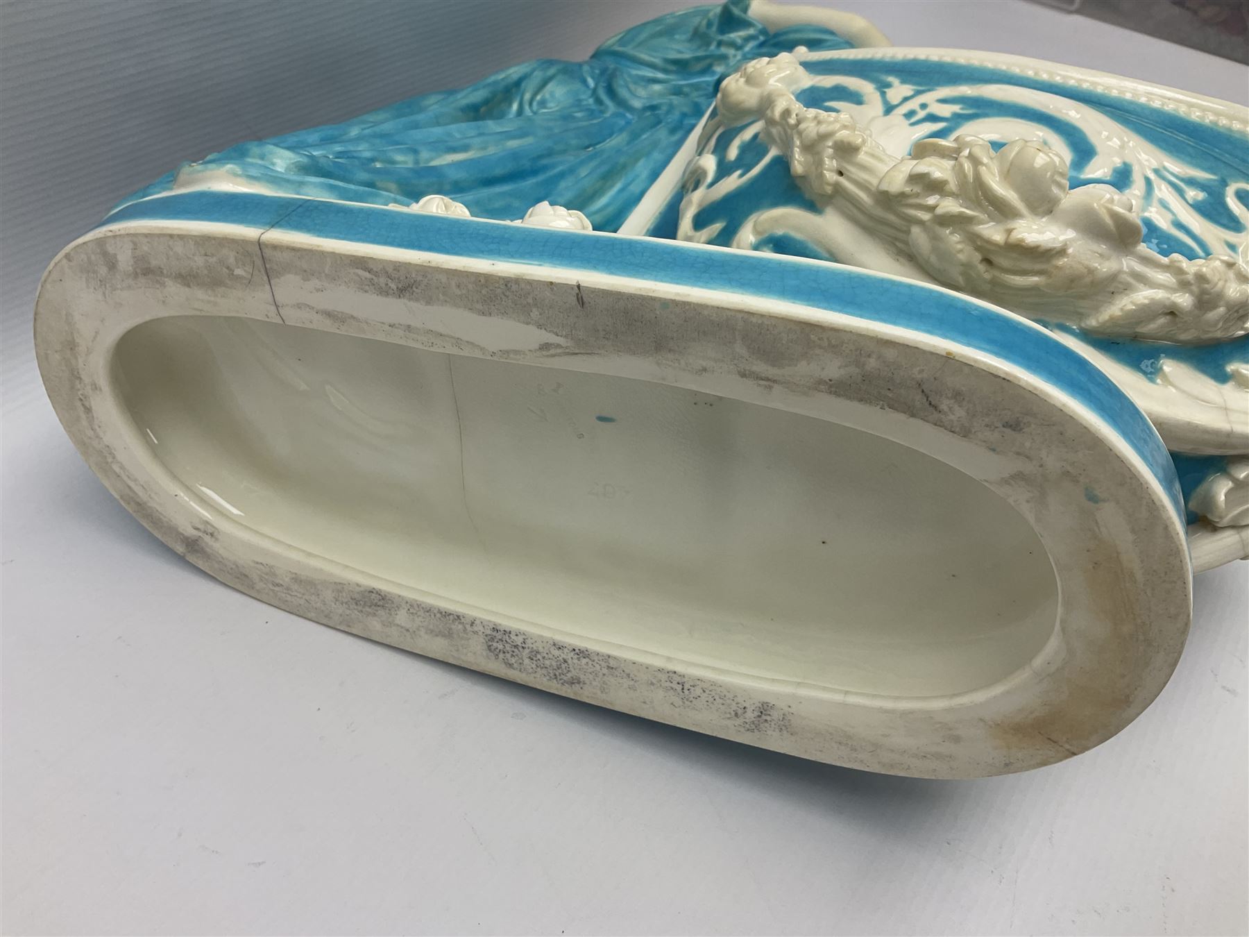 Rare 19th century Minton turquoise glaze majolica 'The Reader' flower holder, after Albert Carrier-Belleuse, modeled as a maiden in classical drapery reading whilst leaning against the pillar back of the helmet shaped cistern detailed with a caryatid and floral swags, the whole upon an oval plinth with Greek key border, with impressed marks beneath, H44cm