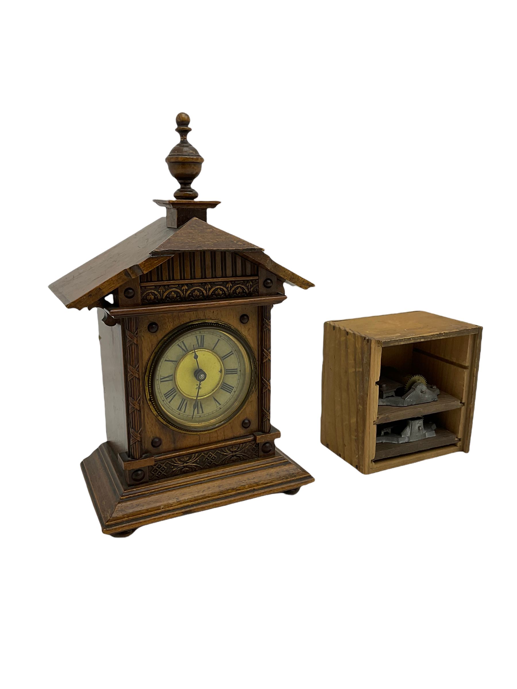 A German musical alarm clock (model 1523/24) made by the Hamburg Amerikanische Uhrenfabrik c1880, in an oak case with an architectural top and finial, two-part dial with a gilt centre, ivorine chapter and steel spade hands, with roman numerals and minute track, case raised on four bun feet, with a thirty-hour balance wheel pin pallet spring driven movement sounding the alarm on a musical movement, key wound and set from the rear. Compete with three different and changeable musical movements in their original box. These clocks would have been sold as here with separate musical movements, it is rare to find them with the original clock.
H30 W17 D11 

	



