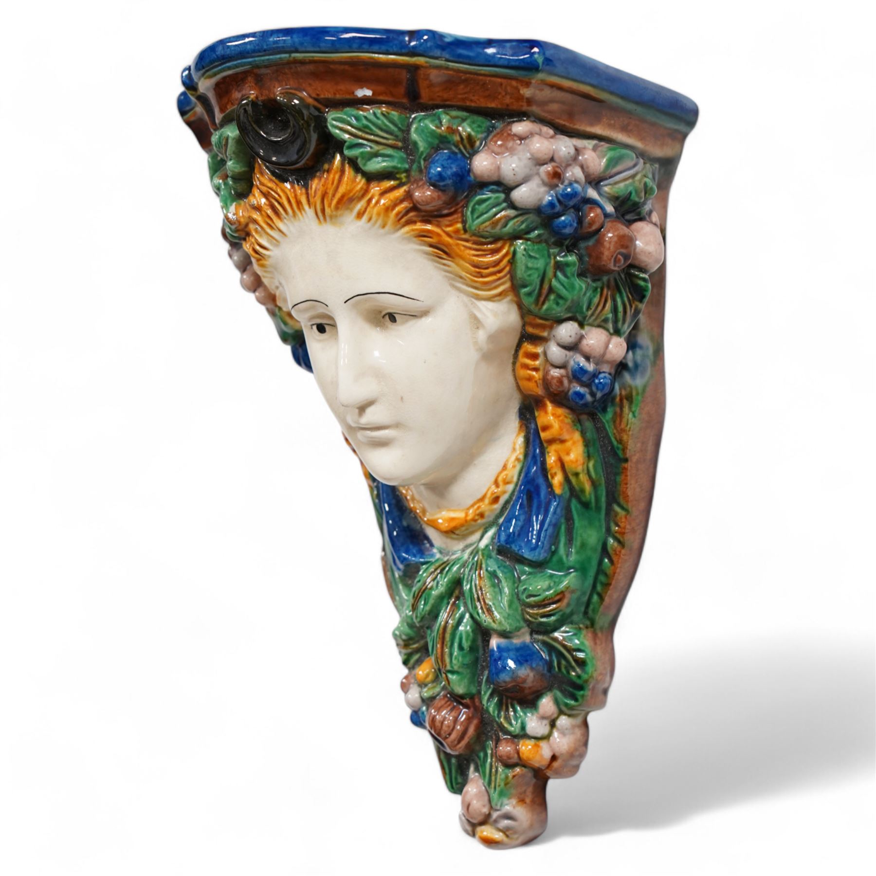 Pair of early 20th century Majolica wall brackets or corbels, formed as two ladies in high relief surrounded by fruit and foliage, on a blue and green ground H30cm 