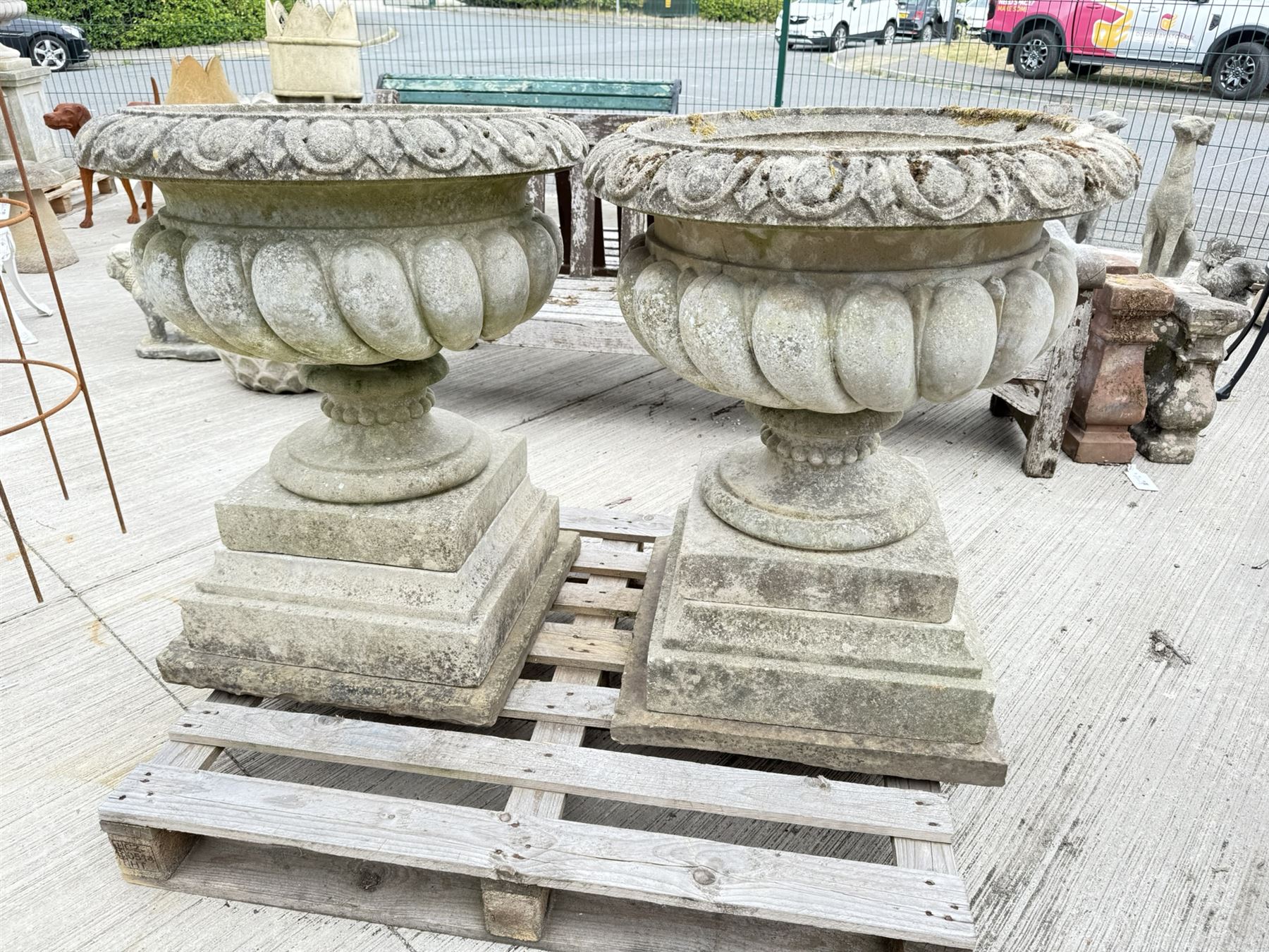 Pair of large weathered Country House Haddonstone garden urns, acanthus carved rim above gadrooned bowl, beaded detailing to the neck, raised on stepped double plinth base
