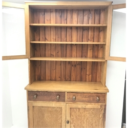  Victorian pitch pine dresser, two glazed doors enclosing fitted shelves, above two drawers and two cupboards, plinth base, W123cm, H216cm, D40cm  